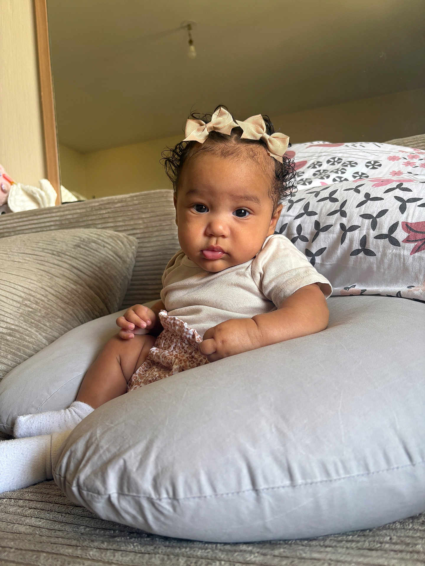 Yvanah participe au concours pour gagner de l'argent avec cette photo : baby, child, infant, couch, pillow, bows, curly_hair, indoor, cozy, cute, sitting, clothing, socks, face, portrait, expression, soft_furniture, home, relaxed, casual