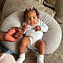 Yvanah a rejoint le concours — aidez-le/la à gagner de superbes lots ! baby, infant, pink_bow, white_onesie, white_socks, hand_holding, plush_pillow, couch, textured_fabric, mirror, reflection, person, indoor, soft_toy, child, cute, portrait, family, tender_moment, cozy