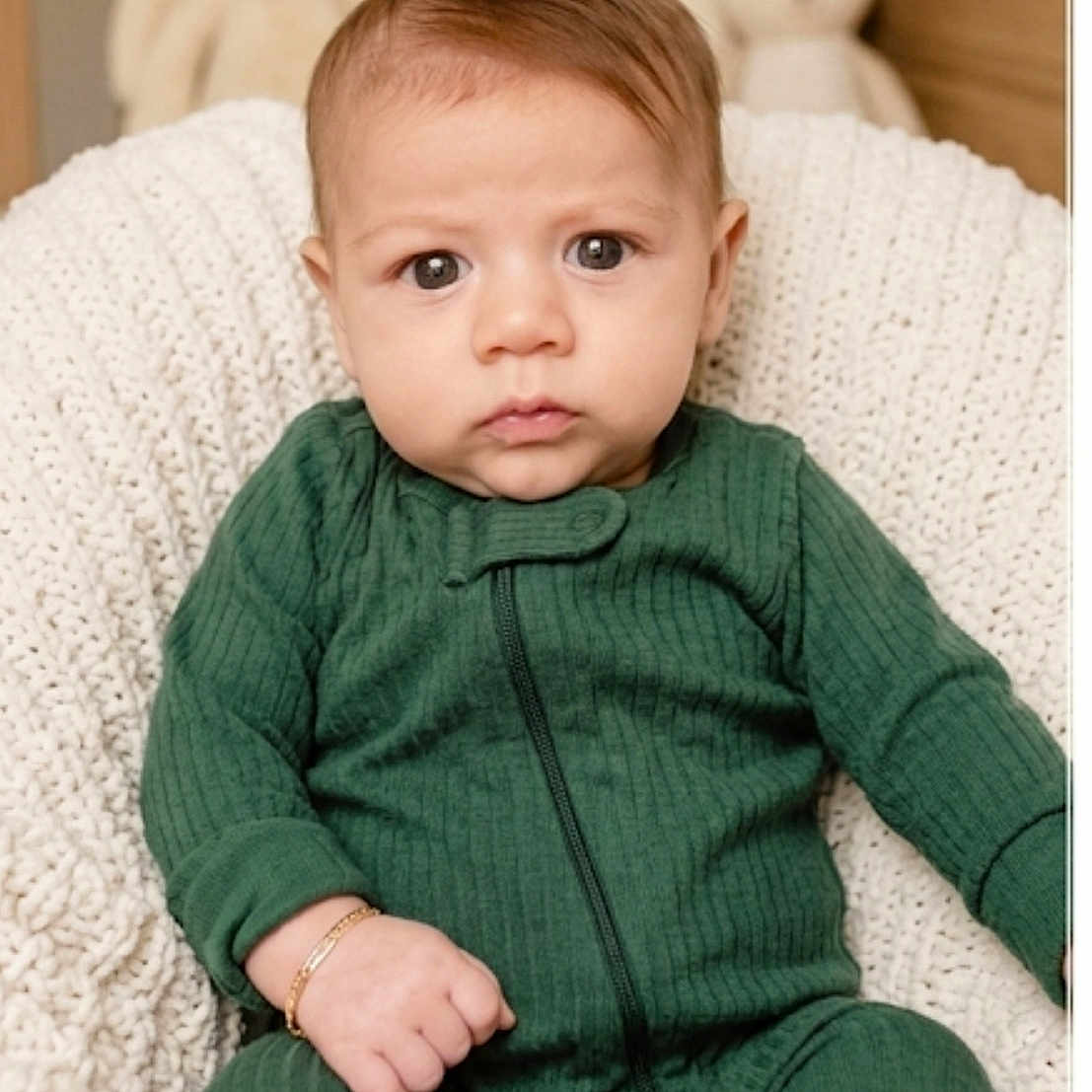 Luciano joined the competition — help win amazing prizes! baby, child, infant, green_outfit, knit_blanket, stuffed_animals, soft_toys, portrait, indoors, seated, cute, young_child, face, expression, furniture, cozy, warm_colors, home, brass_bracelet, focused
