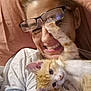 Squeakers is registered to the contest to win money with this photo: casual, cat, closeup, cute, expression, face, glasses, happy, indoor, interaction, kitten, orange_cat, paw, person, pet, playful, relaxed, smile, white_shirt, young