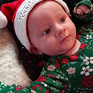 Rosalie is registered to the contest to win money with this photo: baby, infant, christmas_hat, green_clothing, floral_pattern, blanket, cute, holiday, festive, portrait, face, sleepwear, cozy, child, newborn, lying_down, indoors, soft_light, expression, holiday_season