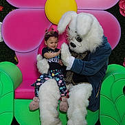Zarra joined the competition — help win amazing prizes! child, toddler, bunny_costume, mascot, flower_backdrop, pink_flower, green_chair, glasses, costume, playful, pigtails, smiling, indoor, seat, colorful, plush, cute, fun, holiday, family