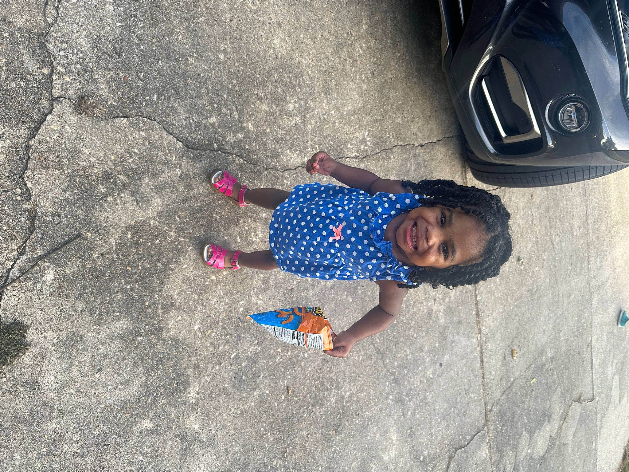 Maliyah is registered to the contest to win money with this photo: asphalt, automotive_lighting, automotive_tire, child, concrete, electric_blue, flooring, joy, leg, person, recreation, rim, road, road_surface, shadow, sidewalk, smile, sneakers, tire, toddler