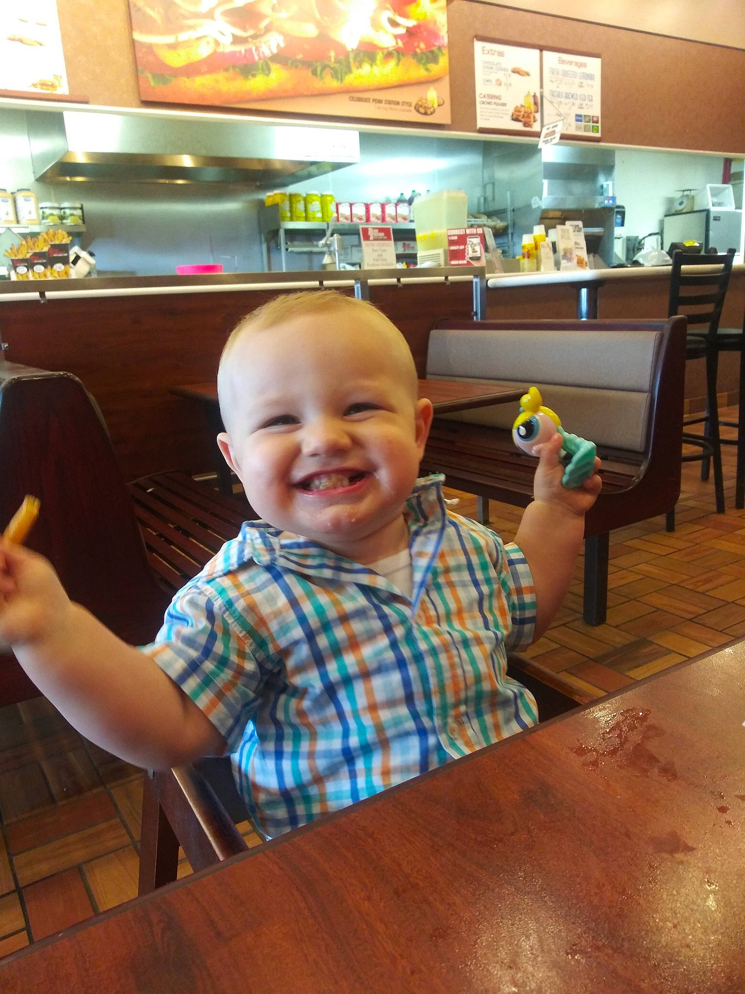 Dustyn is registered to the contest to win money with this photo: baby, child, finger, flooring, fun, joy, person, restaurant, smile, table, toddler