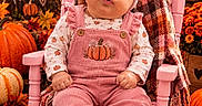 Raven Eclipse is registered to the contest to win money with this photo: baby, child, infant, portrait, sitting, rocking_chair, pink_clothing, pumpkin, autumn, fall, leaves, flowers, harvest, hat, bow, overalls, blanket, indoor, seasonal_decor, smiling