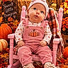 baby, child, infant, portrait, sitting, rocking_chair, pink_clothing, pumpkin, autumn, fall, leaves, flowers, harvest, hat, bow, overalls, blanket, indoor, seasonal_decor, smiling