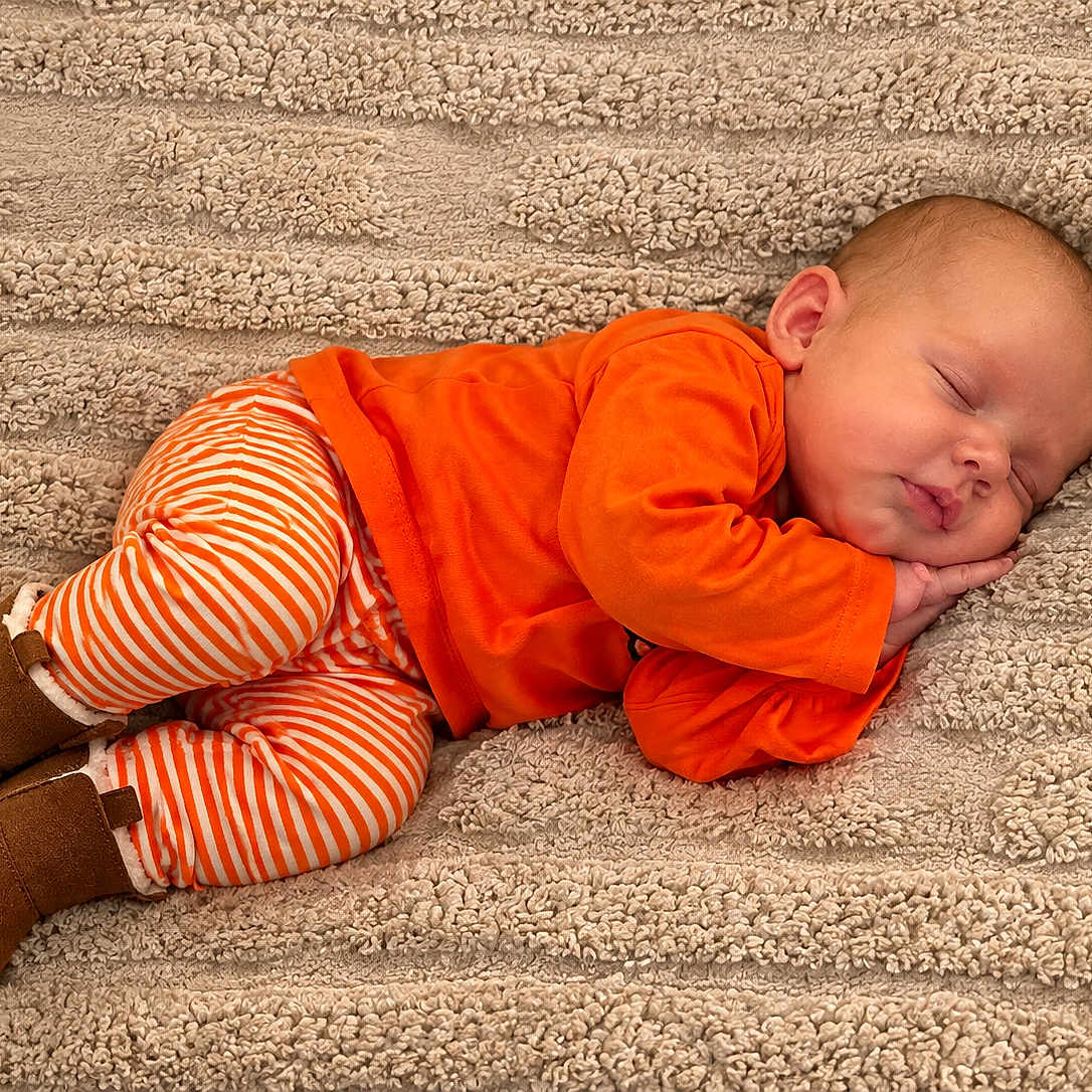 Raven Eclipse joined the competition — help win amazing prizes! baby, blanket, brown_shoes, child, closed_eyes, cozy, curled_up, face, indoor, infant, lying_down, orange_clothing, peaceful, photography, portrait, sleeping, smiling, striped_pants, textured_fabric, warm_colors