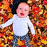 autumn, baby, blue_eyes, child, colorful, fall, happy, infant, leaves, lying_down, nature, open_mouth, outdoors, patterned_pants, photography, portrait, seasonal, smiling, top_view, white_shirt