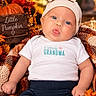 baby, infant, child, portrait, face, blue_eyes, puckered_lips, hat, bow, beanie, white_shirt, text_on_clothing, grandma, autumn, fall, pumpkin, leaves, blanket, outdoor, smiling