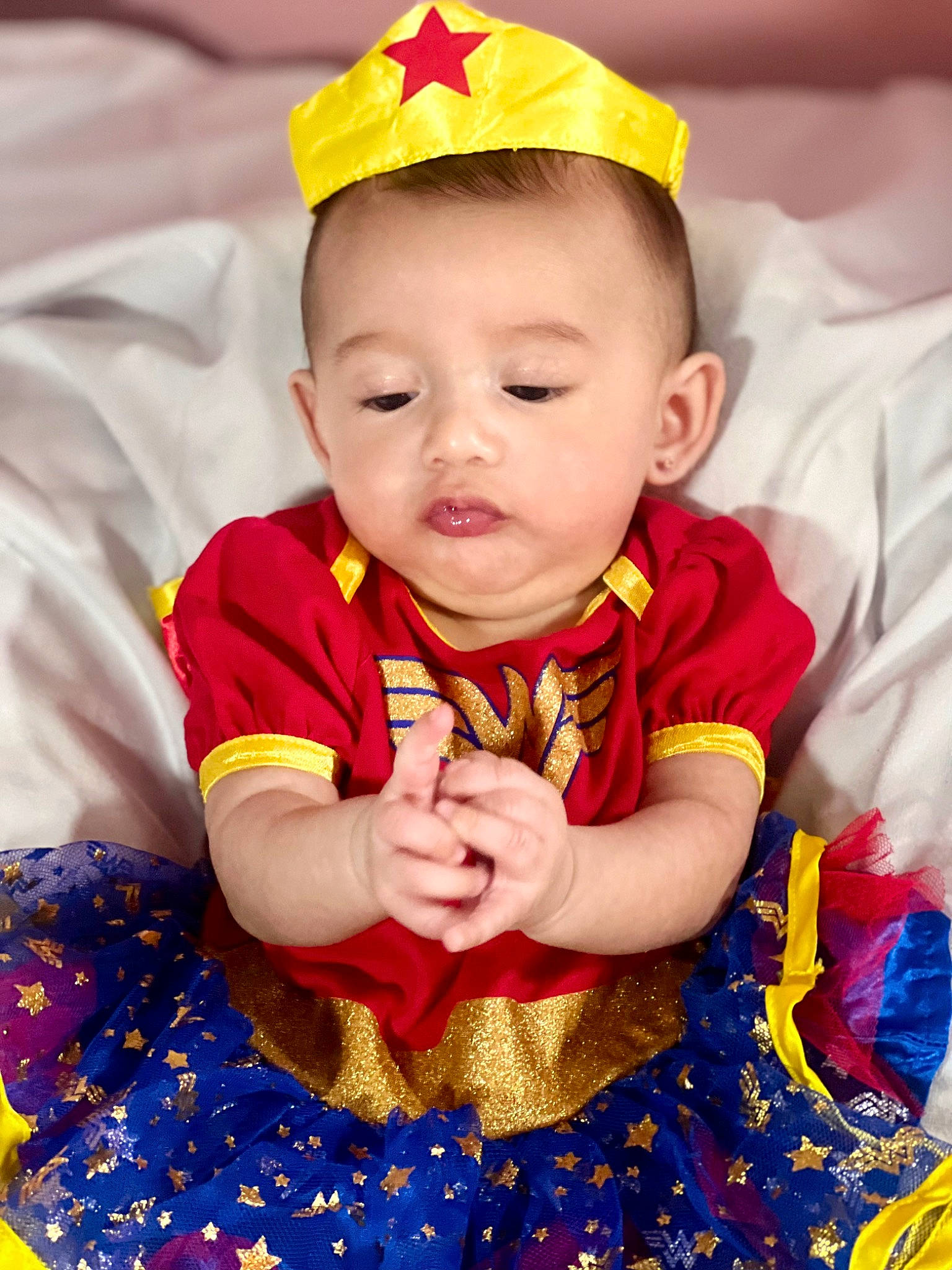 Selena is registered to the contest to win money with this photo: baby, baby_toddler_clothing, child, dress, event, eye, fun, happy, head, headgear, human_body, pattern, person, product, red, skin, sleeve, textile, toddler, white