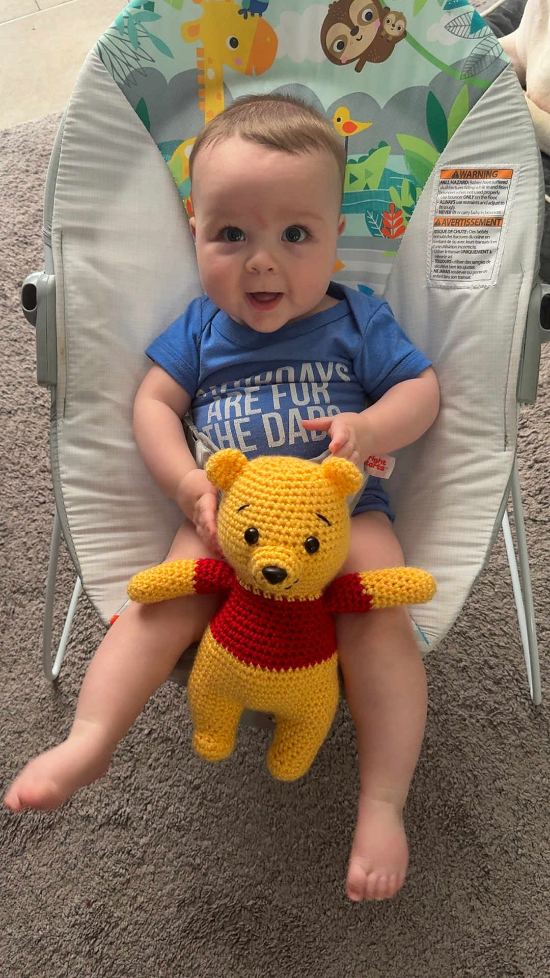 Brayden joined the competition — help win amazing prizes! baby, bouncer, plush_toy, crocheted, winnie_the_pooh, carpet, blue_shirt, indoor, child, smiling, sitting, toy, cute, infant, person, face, legs, feet, happy, colorful