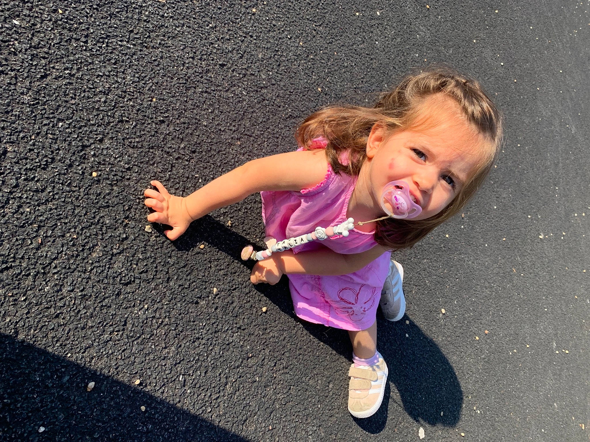 Talia a rejoint le concours — aidez-le/la à gagner de superbes lots ! asphalt, baby_toddler_clothing, child, electric_blue, fun, gesture, grass, happy, human_leg, leisure, magenta, people_in_nature, person, pink, recreation, road_surface, shadow, smile, tar, thumb