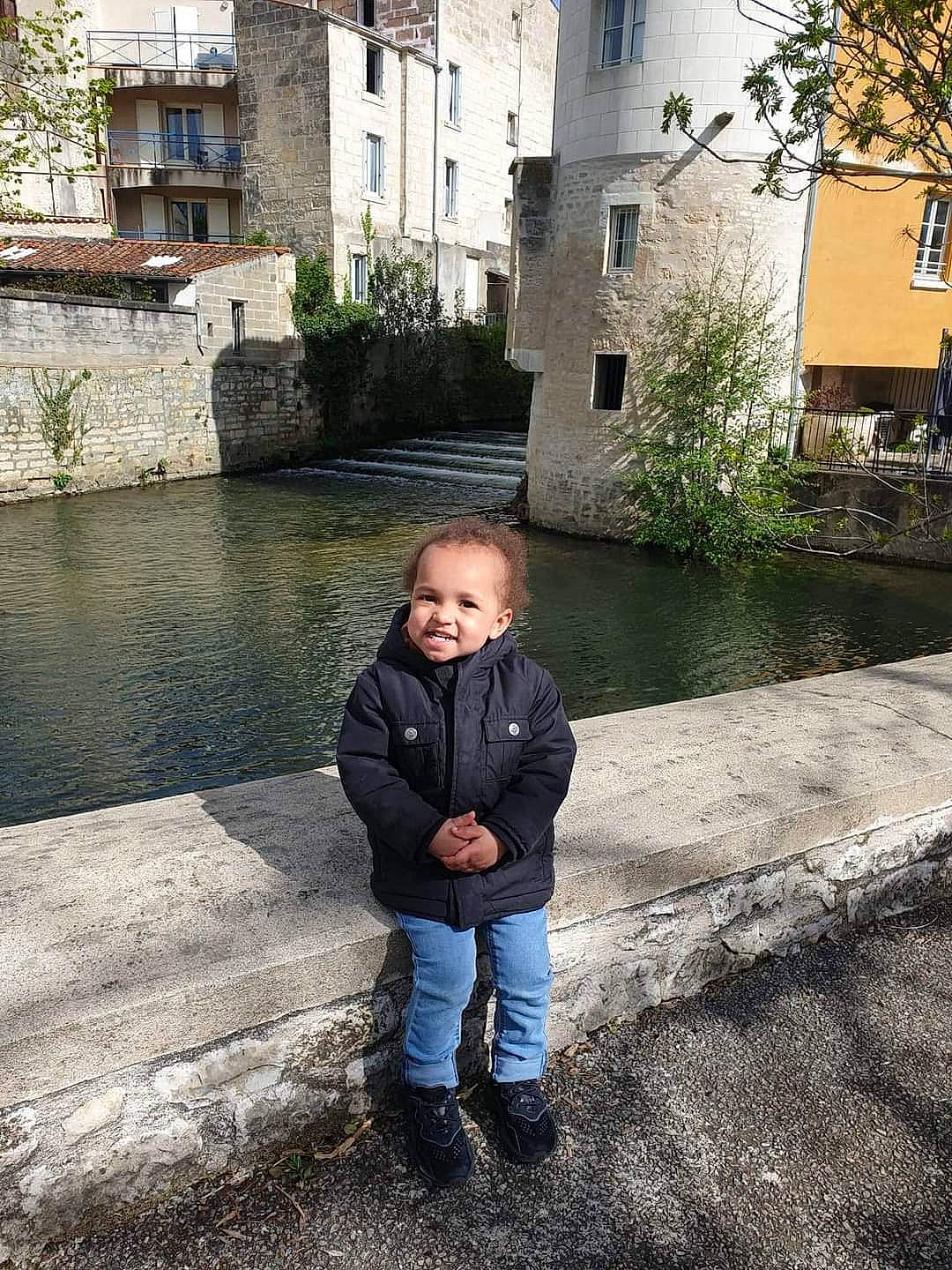 Leeroy participe au concours pour gagner de l'argent avec cette photo : building, cobblestone, denim, flooring, grass, history, house, joy, leisure, person, plant, road_surface, sitting, smile, toddler, tourism, travel, tree, vacation, water