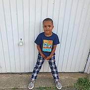 Leeroy a rejoint le concours — aidez-le/la à gagner de superbes lots ! child, boy, standing, pose, blue_shirt, plaid_pants, sneakers, outdoor, concrete, door, white_background, casual_clothing, short_hair, smiling, young, person, fashion, urban, playful, confident
