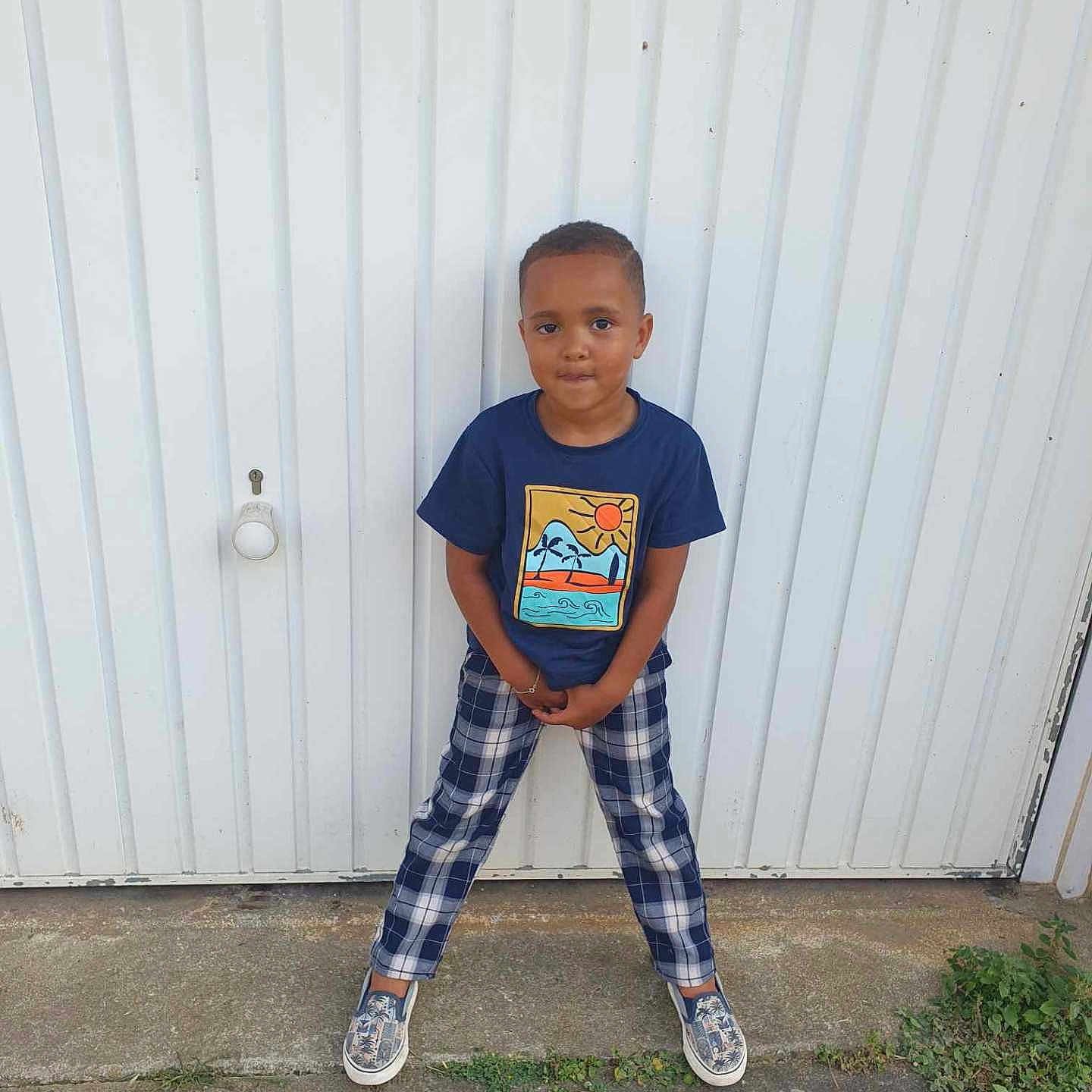 Leeroy a rejoint le concours — aidez-le/la à gagner de superbes lots ! blue_shirt, boy, casual_clothing, child, concrete, confident, door, fashion, outdoor, person, plaid_pants, playful, pose, short_hair, smiling, sneakers, standing, urban, white_background, young