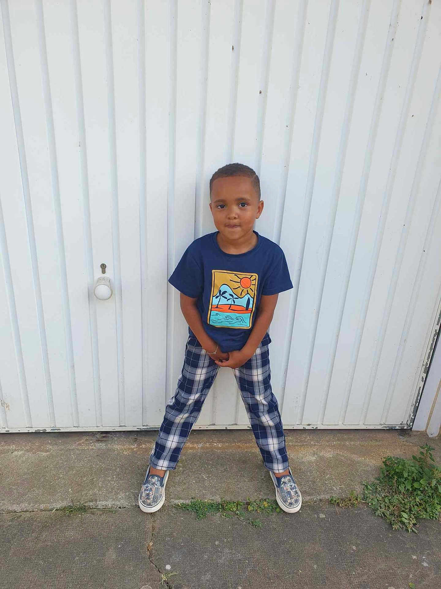Leeroy a rejoint le concours — aidez-le/la à gagner de superbes lots ! child, boy, standing, pose, blue_shirt, plaid_pants, sneakers, outdoor, concrete, door, white_background, casual_clothing, short_hair, smiling, young, person, fashion, urban, playful, confident
