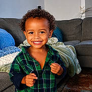 Cloud joined the competition — help win amazing prizes! child, toddler, smiling, curly_hair, green_shirt, plaid_shirt, living_room, blanket, couch, rug, happy, indoors, person, portrait, cute, young_child, home, cozy, furniture, playful