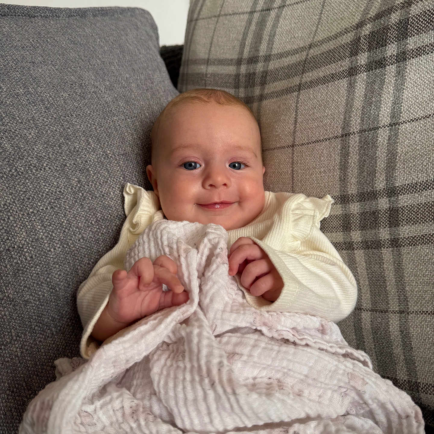 Esmé joined the competition — help win amazing prizes! baby, blanket, child, clothing, comfort, cozy, cushion, cute, face, gray, hands, happy, indoor, infant, plaid, portrait, seated, smiling, soft_texture, young