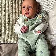 Esmé joined the competition — help win amazing prizes! baby, infant, pillow, blanket, clothing, socks, face, person, portrait, indoor, soft_texture, curious, cute, newborn, seated, hands, head, light, fabric, cozy