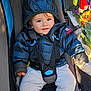 baby, child, colorful, cute, face, hood, infant, outdoor, pants, person, puffer_jacket, seatbelt, seated, smile, straps, stroller, sunlight, toddler, toy, warm_clothing