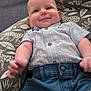 baby, casual_wear, child, clothing, cushion, cute, denim_shorts, face, happy, home, indoors, infant, person, portrait, relaxed, seated, smiling, soft_fabric, striped_shirt, young