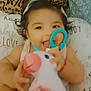 Allison joined the competition — help win amazing prizes! baby, child, closeup, colorful, cushion, cute, hair_clip, happy, indoors, infant, leopard_print, patterned_pillow, person, playful, portrait, sitting, smiling, soft_toy, toy, unicorn