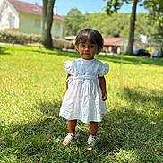 Calyana a rejoint le concours — aidez-le/la à gagner de superbes lots ! child, white_dress, grass, outdoor, sunny, tree, house, blue_sky, portrait, standing, shoes, greenery, daylight, nature, young_child, person, summer, casual, cute, front_view