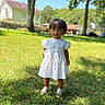 child, white_dress, grass, outdoor, sunny, tree, house, blue_sky, portrait, standing, shoes, greenery, daylight, nature, young_child, person, summer, casual, cute, front_view