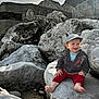 Aloïs a rejoint le concours — aidez-le/la à gagner de superbes lots ! baby, child, smiling, hat, barefoot, rock, rocks, beach, outdoor, nature, sand, clouds, sky, jacket, red_pants, happy, portrait, sunlight, person, casual_clothing