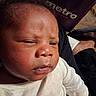 newborn, baby, infant, child, face, portrait, sleepy, side_eye, eyes, nose, mouth, hair, white_outfit, long_sleeves, sitting, close_up, indoor, travel_seat, blanket, photography