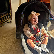 Payton joined the competition — help win amazing prizes! baby, car_seat, carpet, child, cozy, fireplace, floor, furniture, happy, headband, indoor, infant, knitted_sweater, person, portrait, seatbelt, smiling, sunlight, warm_light, white_booties