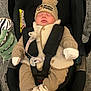 baby, infant, car_seat, sleeping, hat, mickey_mouse, pom_pom, clothing, mittens, socks, plush_toy, zebra, blanket, safety_harness, indoor, cute, cozy, child, person, resting
