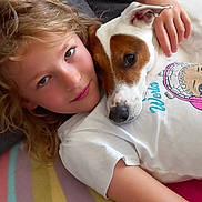 Djul participe au concours pour gagner de l'argent avec cette photo : affection, blanket, brown_patch, casual_clothing, child, closeup, comfort, couch, curly_hair, dog, happy, human, indoor, pet, portrait, relaxed, snuggling, striped_blanket, tshirt, white_dog
