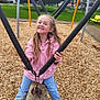 Giulia participe au concours pour gagner de l'argent avec cette photo : child, girl, playground, swing, wood_chips, smile, pink_jacket, jeans, long_hair, chains, outdoors, park, trees, bench, play_equipment, happy, sitting, shoes, daytime, rope