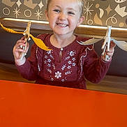 Giulia participe au concours pour gagner de l'argent avec cette photo : casual_clothing, child, cute, fun, furniture, girl, happy, horse, indoor, orange, pattern, person, play, portrait, smiling, table, toy, wall, wings, wooden_toy
