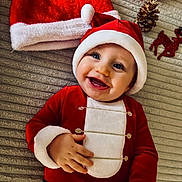 Victor participe au concours pour gagner de l'argent avec cette photo : baby, celebration, child, christmas_outfit, cute, festive, happy, holiday, holiday_decorations, indoor, infant, lying_down, pine_cone, portrait, red_clothing, santa_hat, seasonal, smiling, toy, white_fur_trim
