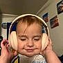 toddler, child, headphones, smiling, indoor, face, hands, music, happy, cozy, wall_art, expression, cute, person, head, blond_hair, shirt, closeup, portrait, home