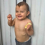 Noah is registered to the contest to win money with this photo: toddler, child, smile, shirtless, bread, hand_gesture, standing, jeans, hair, face, background, panel, playful, happy, cute, skin, person, expression, young, indoors