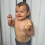 toddler, child, smile, shirtless, bread, hand_gesture, standing, jeans, hair, face, background, panel, playful, happy, cute, skin, person, expression, young, indoors