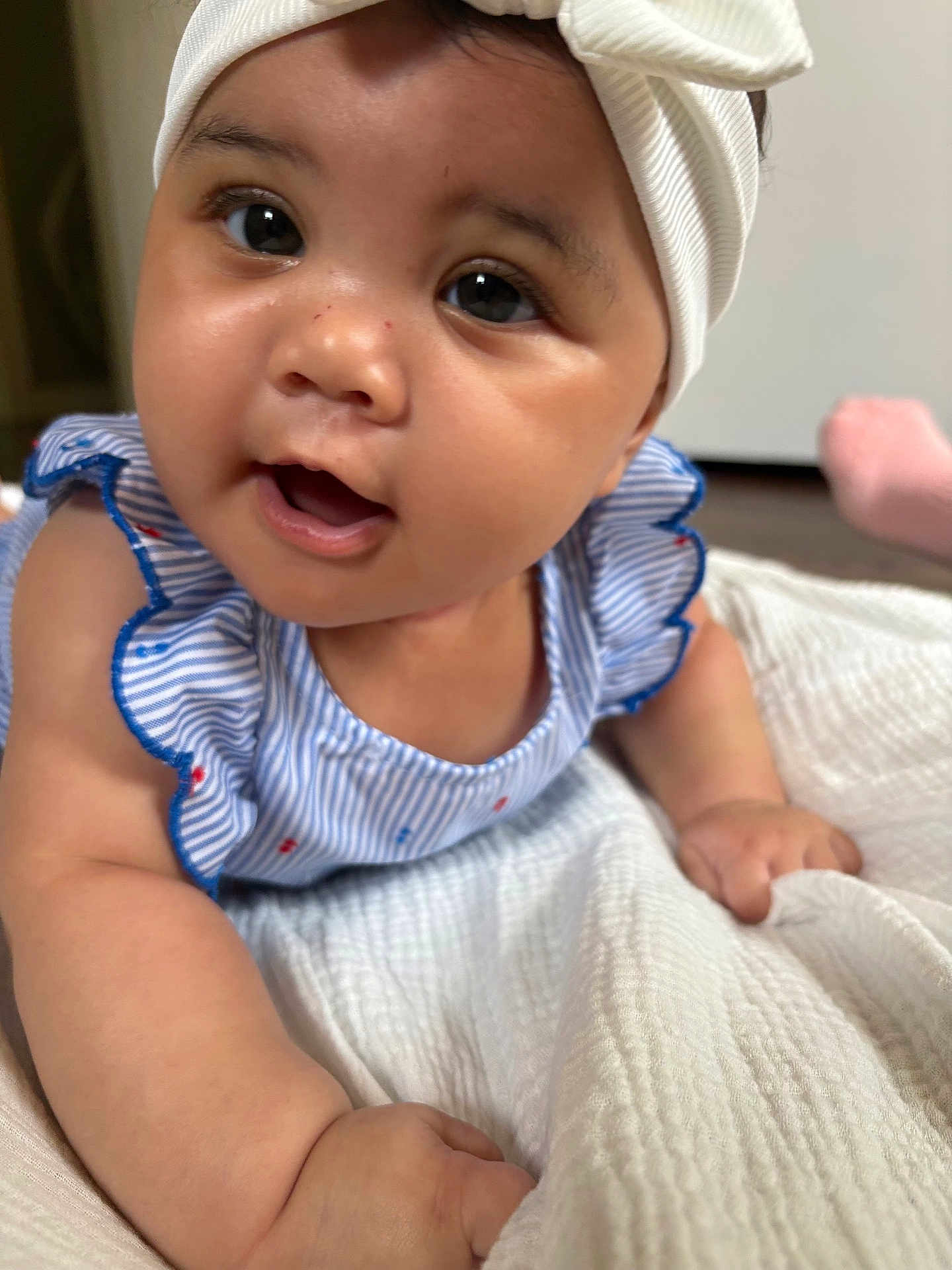 Nara Holloway joined the competition — help win amazing prizes! baby, infant, child, headband, blue_striped_clothing, white_blanket, close_up, face, eyes, hands, cute, indoors, skin, smiling, ruffles, portrait, lying_down, soft_texture, adorable, human