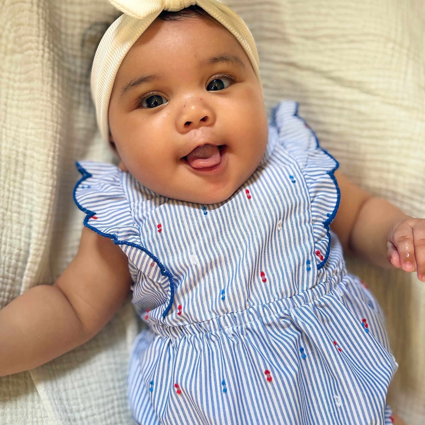 Nara joined the competition — help win amazing prizes! arm, baby, blanket, bow, cheeks, child, closeup, cute, dress, happy, headband, indoors, infant, lying_down, portrait, skin, smiling, soft_texture, striped_clothing, tongue