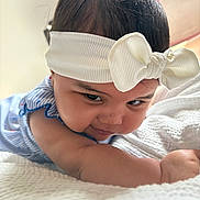 Nara joined the competition — help win amazing prizes! baby, headband, bow, white, blanket, infant, cute, face, expression, arm, skin, lying, child, indoors, soft_light, clothing, portrait, closeup, smile, person