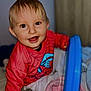 Maylan participe au concours pour gagner de l'argent avec cette photo : baby, child, smile, happy, indoor, toy, clothing, red_sweater, face, eyes, blanket, bed, play, person, hoodie, cute, infant, portrait, young_child, home
