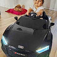 Ivana participe au concours pour gagner de l'argent avec cette photo : toddler, toy_car, audi, black_car, indoor, wooden_floor, dog, red_cushion, child, happy, smiling, short_hair, white_shirt, steering_wheel, pet, living_room, flooring, cute, playtime, small_dog