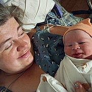 Patricio is registered to the contest to win money with this photo: mother, newborn, baby, hospital, bed, blanket, hat, smile, woman, person, indoor, closeup, love, family, skin, face, healthcare, comfort, lying_down, tender_moment