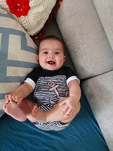 Nia participe au concours pour gagner de l'argent avec cette photo : baby, baby_toddler_clothing, child, comfort, elbow, eye, flash_photography, happy, head, human_leg, linens, pattern, person, plaid, sitting, skin, sleeve, smile, t_shirt, textile