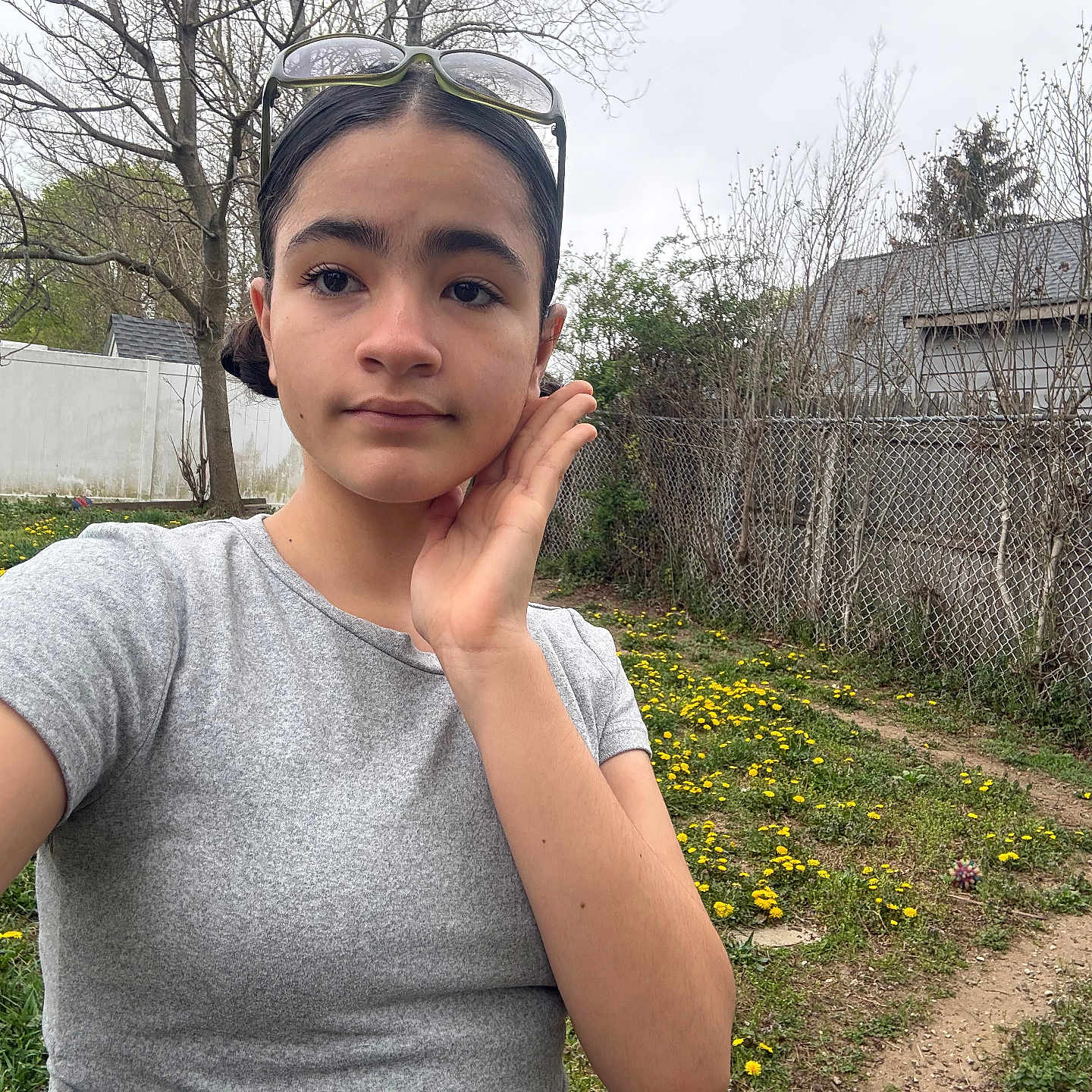 Aniya joined the competition — help win amazing prizes! child, outdoor, selfie, person, flowers, garden, grass, tree, fence, building, grey_tshirt, glasses, hand, face, nature, spring, casual, young, portrait, daytime