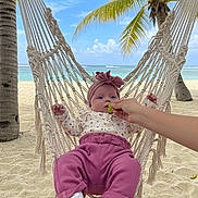 Brynlee joined the competition — help win amazing prizes! baby, infant, hammock, beach, sand, palm_tree, ocean, sky, clouds, hand, grape, headband, pink_pants, floral_top, white_socks, relaxation, tropical, vacation, outdoor, nature
