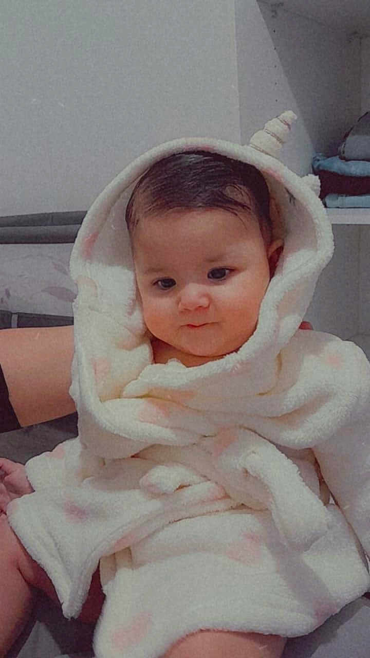 Sofia a rejoint le concours — aidez-le/la à gagner de superbes lots ! baby, child, hooded_robe, fluffy_clothing, indoor, cute, infant, soft_texture, person, face, smile, cozy, sitting, young_child, warm_clothing, apparel, adorable, gentle_lighting, human, portrait