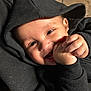 Devonte is registered to the contest to win money with this photo: baby, baby_hands, black_clothing, child, closeup, cozy, cute, face, hands, happy, hoodie, indoors, infant, joyful, person, portrait, smiling, warm_lighting, wood_background, young_child